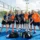 Groupe de joueurs de padel sur un court extérieur, prêt pour l’entraînement, avec sacs et bouteilles au sol. modèles en maillots t-shirts orange et bleu. - intégré: comment organiser un événement sportif réussi