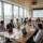 Salle de réunion avec vue urbaine, participants en réunion autour d’une table longue, ordinateurs et documents. lieu séminaire entreprise idéal pour démarrer des échanges.