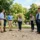 Groupe de collègues debout sur un boulodrome extérieur, lançant des boules de pétanque dans une aire de jeu, ambiance conviviale et verdure autour. intégration: organiser un tournoi de pétanque en entreprise.