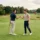 Deux joueurs de golf se serrent la main sur le green, chacun tenant son club, symbolisant le golf inter entreprise et l’esprit d’équipe.