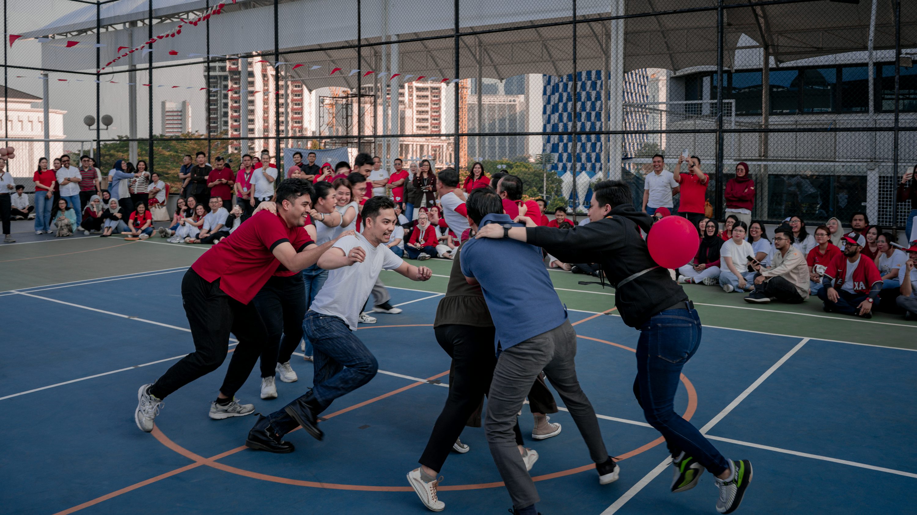 Un groupe de personnes en train de s'affronter dans un jeu collectif sur un terrain de sport couvert, entouré de spectateurs.
