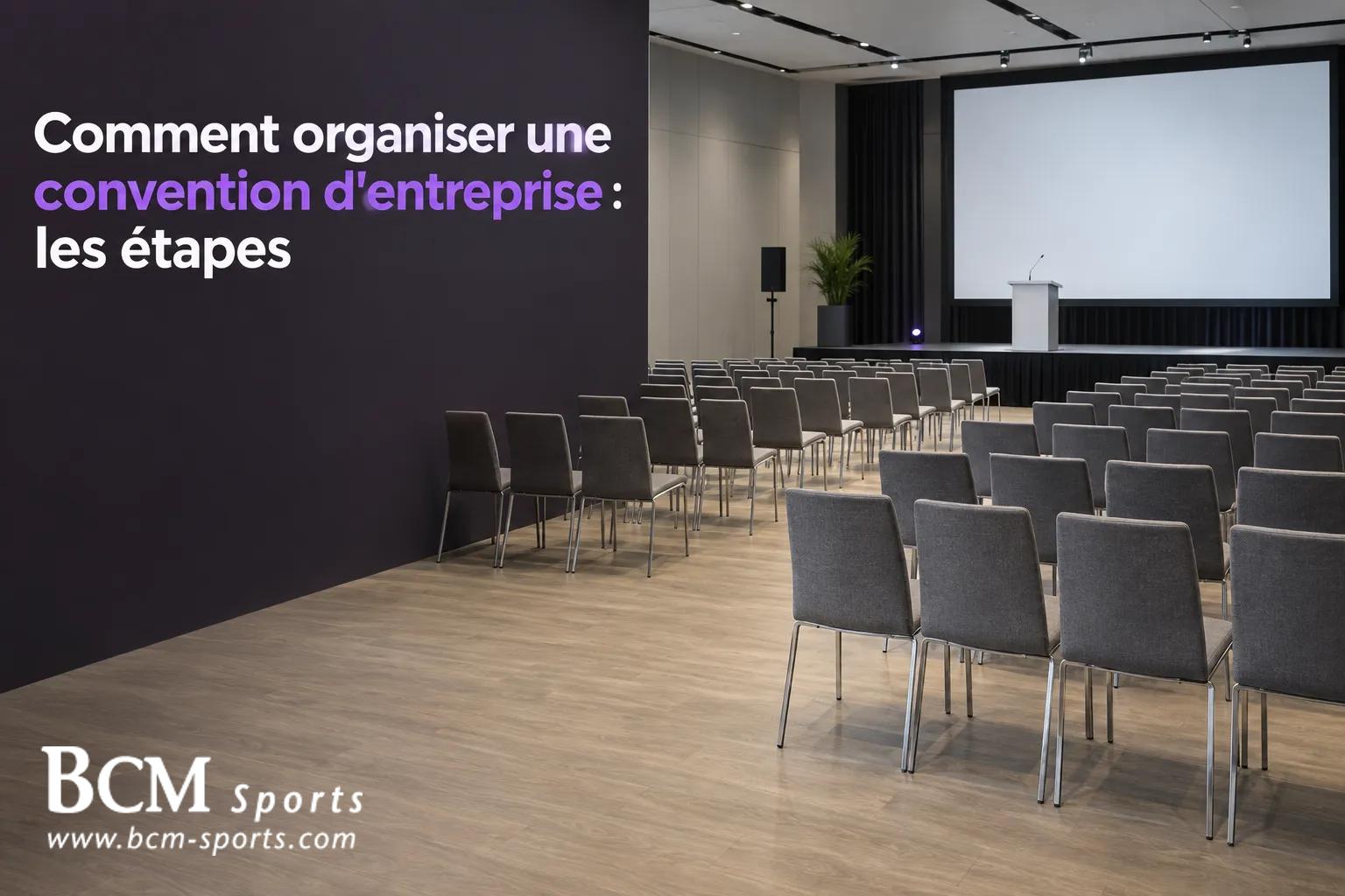 Salle de conférence vide avec un écran et une scène, et un mur noir affichant le titre "Comment organiser une convention